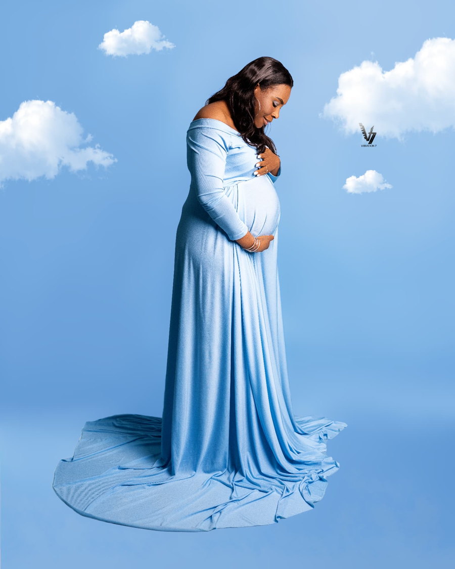 Maternity portrait in a blue gown against a sky backdrop